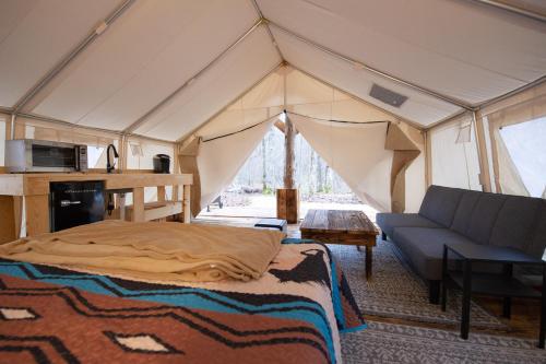 a tent with a bed and a couch in a room at Creekside Glamping Current River Mark Twain Forest in Doniphan