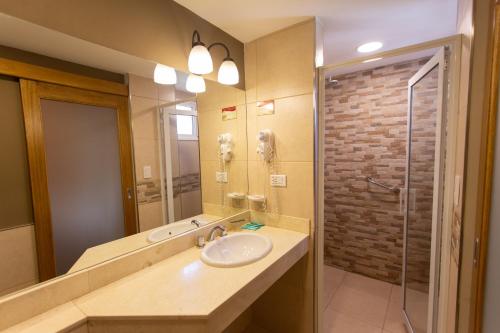 a bathroom with a sink and a glass shower at Hotel Suizo in Neuquén