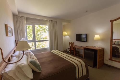 Habitación de hotel con cama y ventana en Hotel Suizo en Neuquén