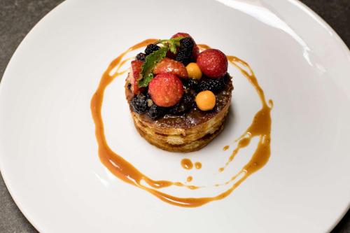 a white plate with a dessert with fruit on it at Radisson Serviced Apartments Antananarivo City Centre in Antananarivo