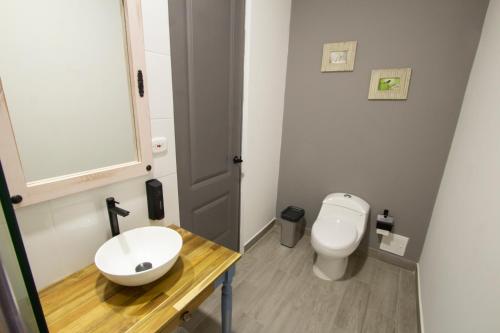 a bathroom with a white toilet and a sink at Hotel Pajara Pinta in Cali
