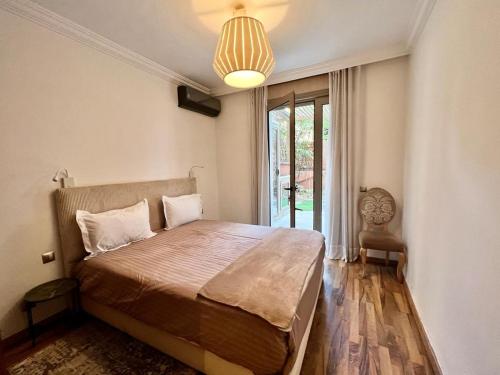 a bedroom with a large bed with a large window at Superbe Appartement avec terrasse et jardin au cœur de l’hivernage in Marrakesh