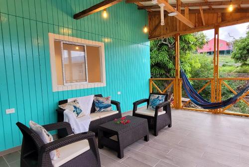 a patio with chairs and a hammock on a green wall at Colorful Garden House in Providencia