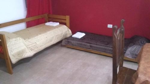 2 Betten in einem Zimmer mit roten Wänden in der Unterkunft Mi Lugar in Olavarría