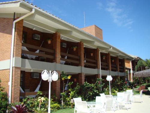 a building with white tables and chairs in front of it at Pousada Ponta do Lobo in Balneário Camboriú