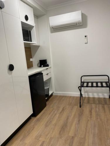 a room with a kitchen with a refrigerator and a table at Cattlemans Country Motor Inn & Serviced Apartments in Dubbo