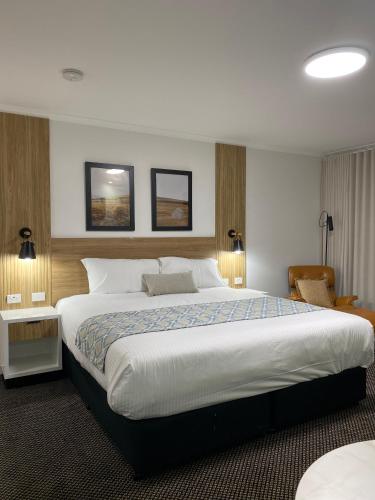 a bedroom with a large bed and two pictures on the wall at Cattlemans Country Motor Inn & Serviced Apartments in Dubbo