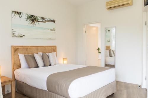 a white bedroom with a large bed and a mirror at Agnes Water Beach Club in Agnes Water
