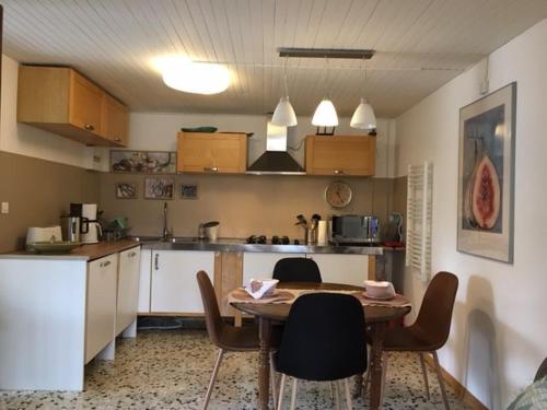 une cuisine avec une table et des chaises dans une pièce dans l'établissement Gîte douillet près canal de Berry: Wifi, jardin fleuri, parking, tout compris, lits faits à l'arrivée - FR-1-586-25, à Drevant