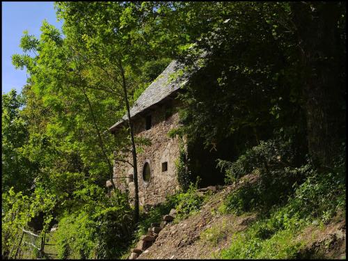 un antiguo edificio de piedra en una colina con árboles en Malrieu, en Le Fel