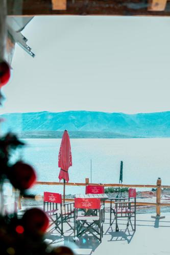a table and chairs and a red umbrella and water at Hotel Spa Nieves Del Cerro in Caviahue