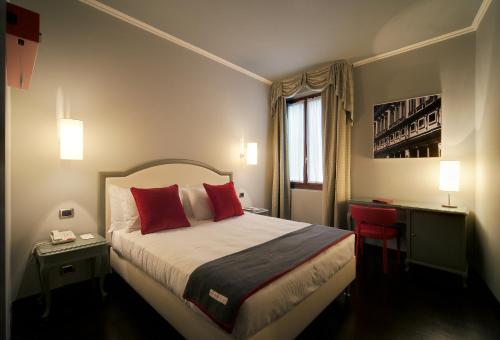 a hotel room with a bed with red pillows and a window at Hotel Rosso23 - WTB Hotels in Florence