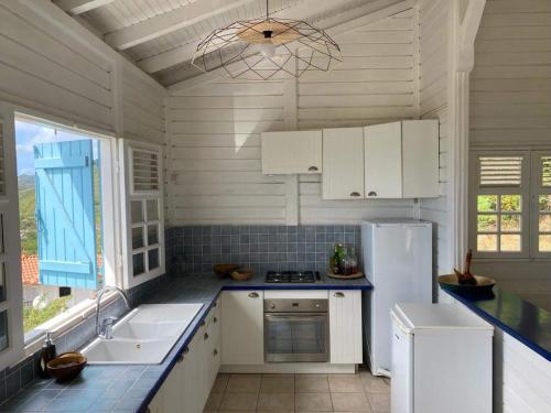 a kitchen with white cabinets and a white refrigerator at VILLA KARAT in Le Diamant