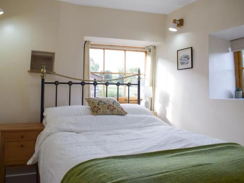 a bedroom with a large white bed with a window at The Granary in Clee Saint Margaret