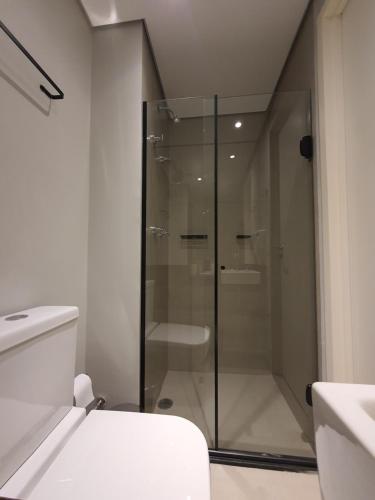 y baño con ducha de cristal y aseo. en Studio Perdizes Allianz, en São Paulo