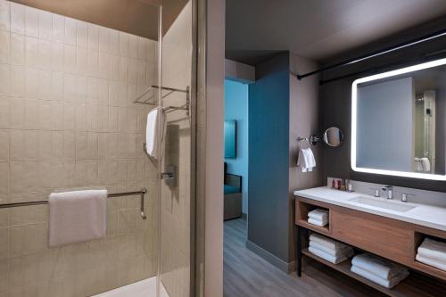 uma casa de banho com um lavatório e um chuveiro com um espelho. em Austin Marriott Downtown em Austin