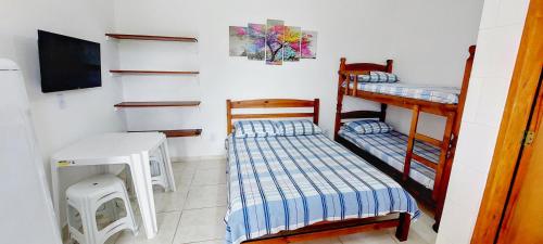 a room with two bunk beds and a flat screen tv at Recanto Bela Vista in Peruíbe
