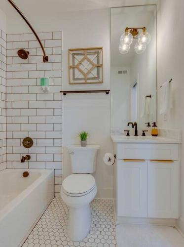 a bathroom with a toilet and a tub and a sink at Luxury Downtown Nash/Roofdeck/11 Beds in Nashville