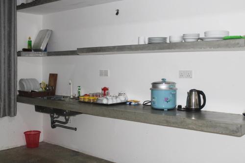 a kitchen shelf with dishes and a pot on it at Savendro Villa Hikkaduwa in Hikkaduwa