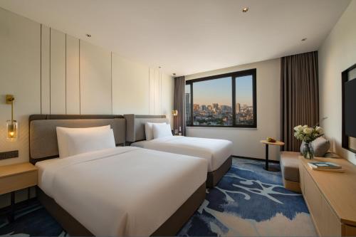 two beds in a hotel room with a window at Guangzhou Hotel in Guangzhou
