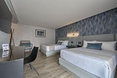Habitación de hotel con 2 camas y escritorio en Hotel Estancia Business Class, en Guadalajara