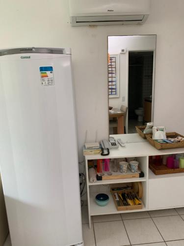 a white refrigerator in a room with a mirror at Flat Beach Class Resort Muro Alto in Porto De Galinhas
