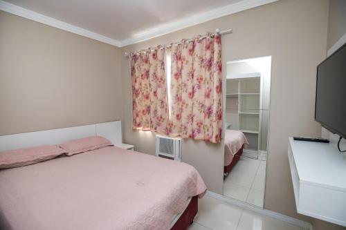 um pequeno quarto com uma cama e uma janela em Apartamento AV. Brasil Frente Sh. Atlântico em Balneário Camboriú