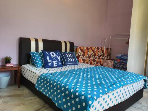 a bedroom with a bed with blue and white sheets at Homey Homestay in Tanjong Sepat