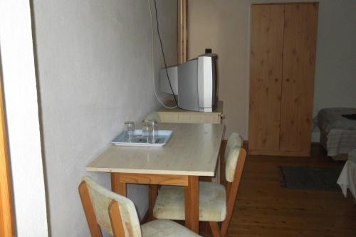 uma mesa com cadeiras e uma televisão na parede em Fenyő Panzió em Makó