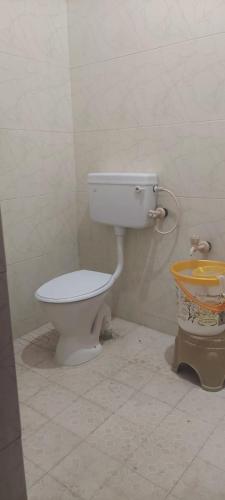a bathroom with a white toilet and a bucket at Doctor's Homestay in Tiruvannāmalai