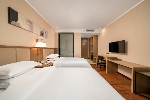 a hotel room with two beds and a flat screen tv at Guangzhou Boyi Hotel in Guangzhou