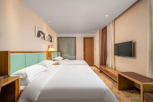 a hotel room with two beds and a flat screen tv at Guangzhou Boyi Hotel in Guangzhou