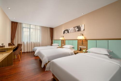 a hotel room with four beds and a desk at Guangzhou Boyi Hotel in Guangzhou