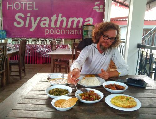 a man sitting at a table with plates of food at Hotel Siyathma polonnaruwa in Polonnaruwa