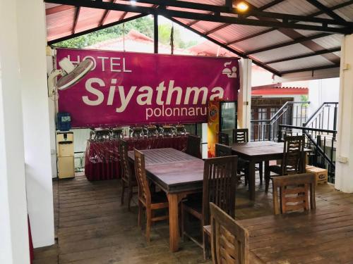 a restaurant with tables and chairs and a red sign at Hotel Siyathma polonnaruwa in Polonnaruwa