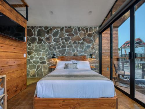 a bedroom with a bed and a stone wall at Sirius Valle in Valle de Guadalupe
