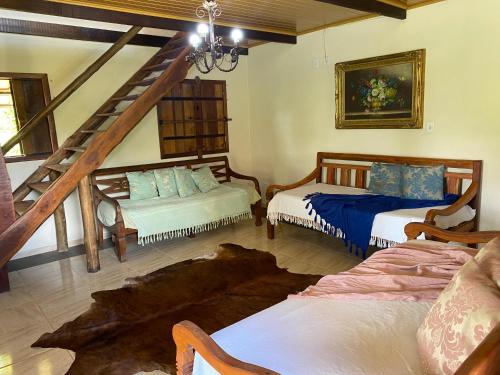 ein Wohnzimmer mit 2 Betten und einer Treppe in der Unterkunft Recanto da Represa Carrancas in Carrancas