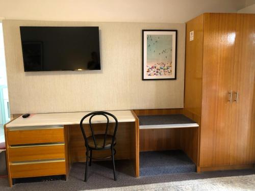 a room with a desk with a chair and a tv at Avaleen Lodge Motor Inn in Nowra