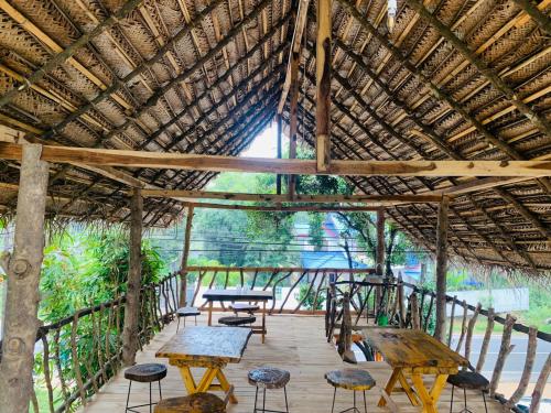 a wooden deck with tables and chairs under a thatched roof at Ruins View Holiday Resort in Polonnaruwa