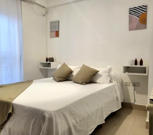 1 dormitorio con 1 cama grande con sábanas y almohadas blancas en deanfunes home en Salta