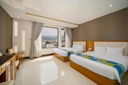 a hotel room with two beds and a large window at Anh Phuong Hotel & Apartment in Da Nang