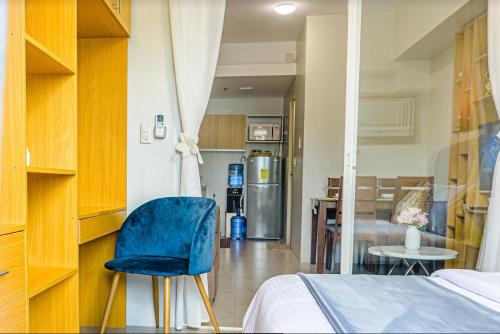 a bedroom with a blue chair and a kitchen at 1 bedroom condo unit at Sundance Residences in Cebu City