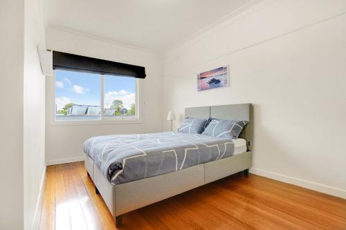 a white bedroom with a bed and a window at Hotham Heights in Warrnambool