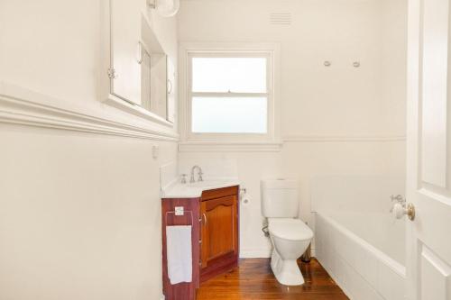 a bathroom with a toilet and a sink and a window at Hotham Heights in Warrnambool