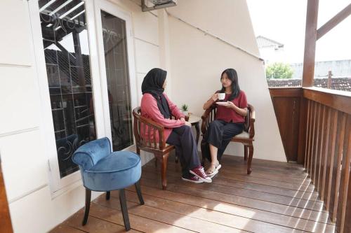 INEZ Homestay Prawirotaman Yogya في Timuran: وجود سيدتان جالستان على شرفة المنزل