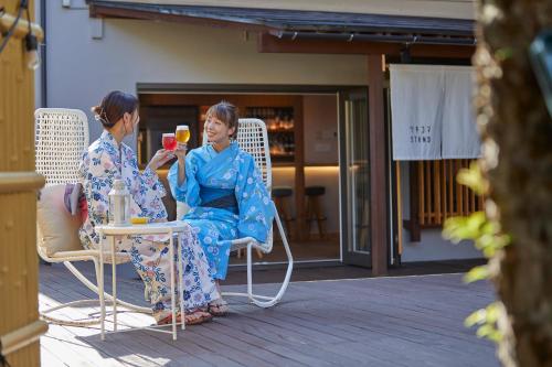 two women sitting in chairs on a patio with drinks at Ichiraku tendo spa & brewery in Tendo