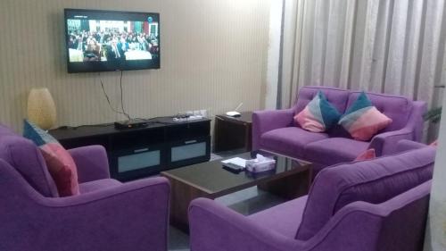 a living room with purple chairs and a tv at شقق رهف السالميه in Kuwait