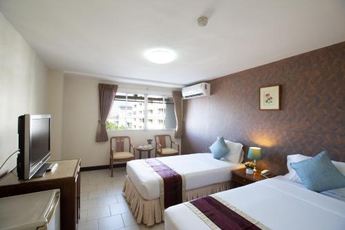 a hotel room with two beds and a television at D-haus Ladprao Residence in Bangkok