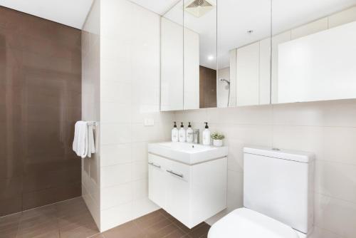 a white bathroom with a toilet and a sink at The Alta Apartments by Urban Rest in Sydney