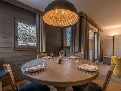 une salle à manger avec une table en bois et un lustre dans l'établissement Superbe appartement à Méribel avec garage privatif et balcon - FR-1-613-12, à Méribel